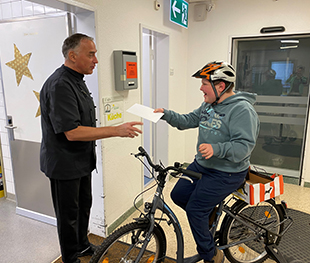 Junge mit Helm auf dem Fahrrad übergibt einen Brief