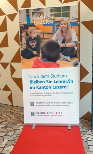 Roter Teppich mit Stellwand auf der steht: Nach dem Studium: Bleiben Sie Lehrer/in im Kanton Luzern!